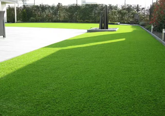 Moderne Terrasse mit heller Steinplattenfläche und angrenzendem Kunstrasen