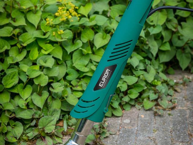 Unkrautbrenner im Einsatz zwischen Bodendeckern am Wegrand