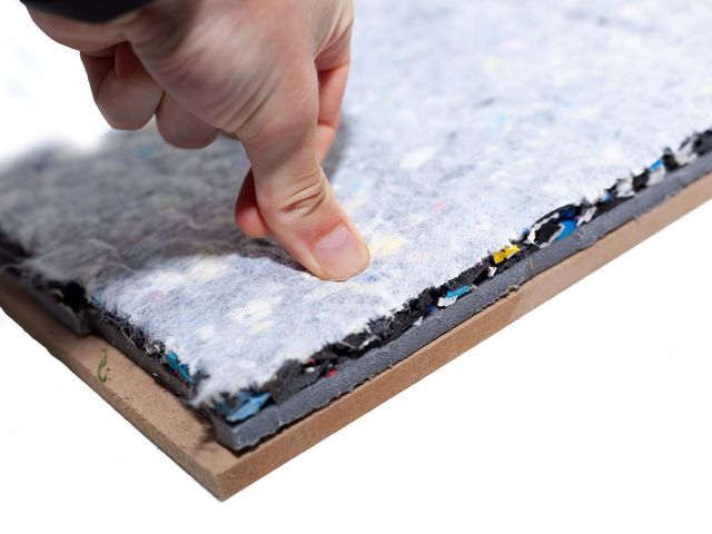 Eine Hand drückt auf die Falldämpfungsplatte und zeigt, wie stark das Material nachgibt
