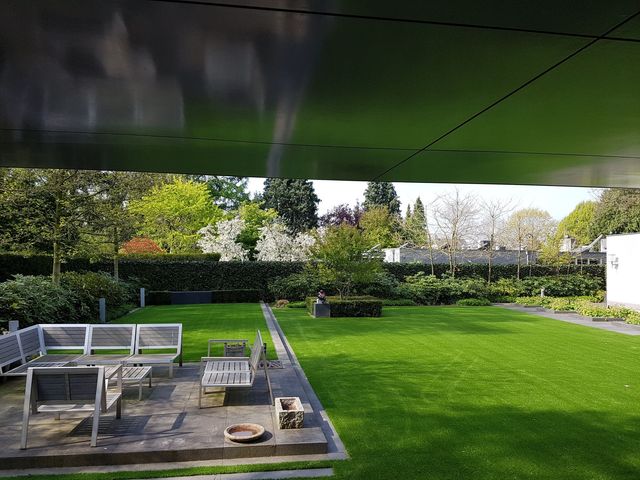Blick von der überdachten Terrasse über die Sitzgruppe auf die Kunstrasenfläche