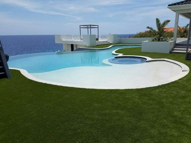 Poolterrasse mit Meerblick, die Flächen rund um das Becken sind begrünt