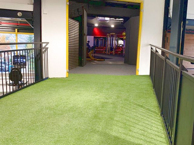 Kunstrasenfläche im Gym vor einer Reihe Laufbänder