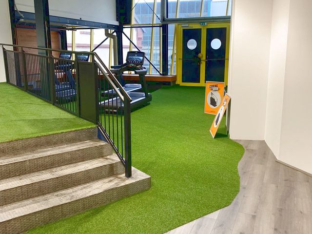 Kunstrasenbahn in einem Fitnessstudio, im Hintergrund Trainingsgeräte