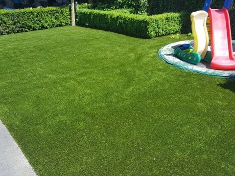 Kunstrasenfläche im Garten mit Kinderrutsche und aufblasbarem Planschbecken